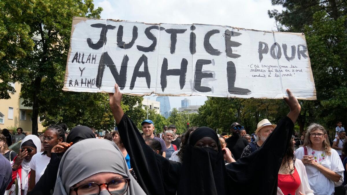 A woman shows a poster 'Justice for Nahel' during a march for 17-year-old Nahel in Nanterre, outside Paris. - AP