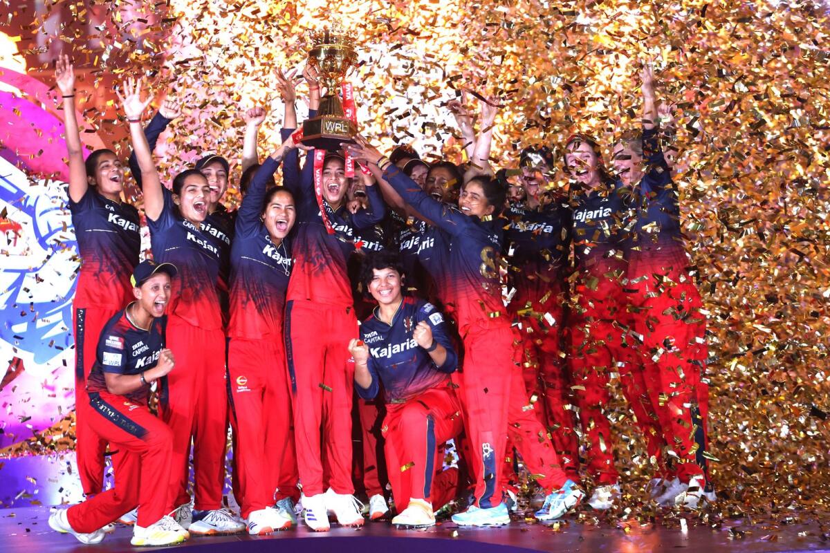 Royal Challengers Bangalore players celebrate with the trophy after winning the final. — WPL