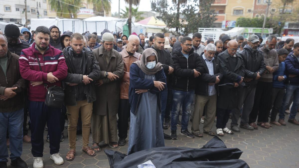 Palestinians pray for the relatives killed in the Israeli bombardments of the Gaza Strip in front of the morgue of the Al Aqsa Hospital in Deir al Balah. — AP