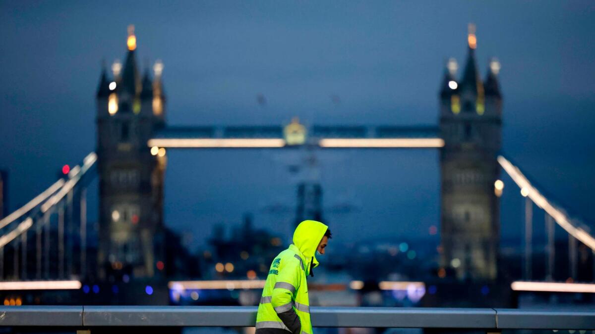 A pedestrian crosses London Bridge with Tower Bridge in the background in London on November 25, 2020.