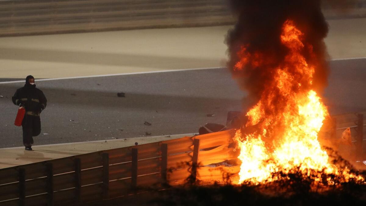 A fire marshal rushes to put out a fire on Romain Grosjean's car during the Bahrain Formula One Grand Prix. (AFP)