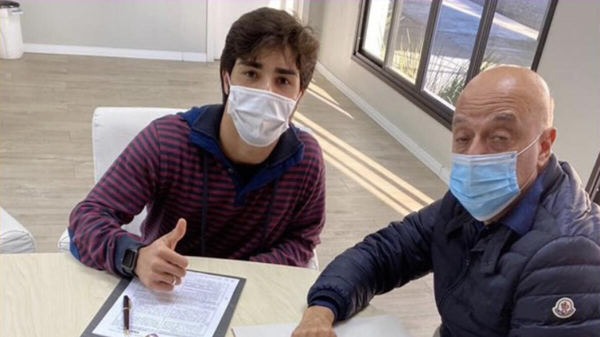 Brazilian teenager Erik Jorgens de Menezes (left)  signs the contract. - (Al Ain FC Twitter)
