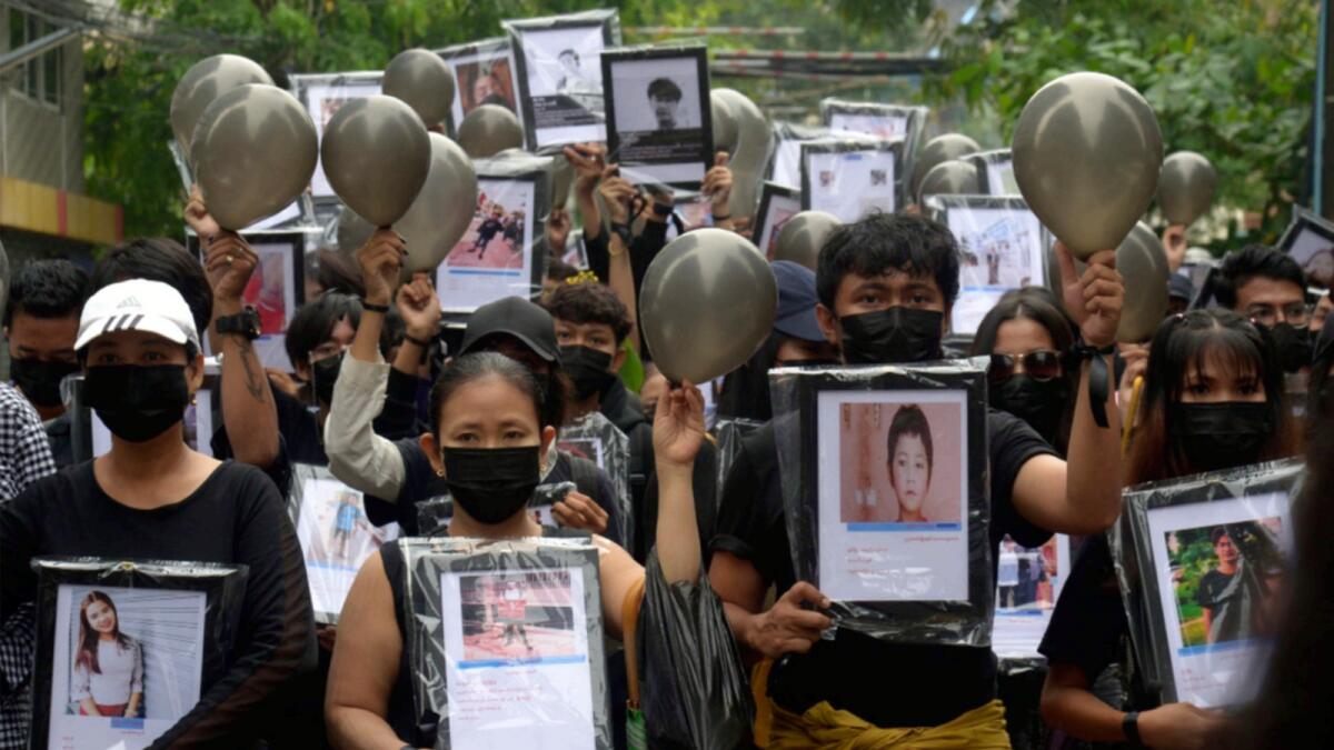 Anti-coup protesters holding pictures of those who died during a protest against the military offer prayers for them, in Yangon. — AP