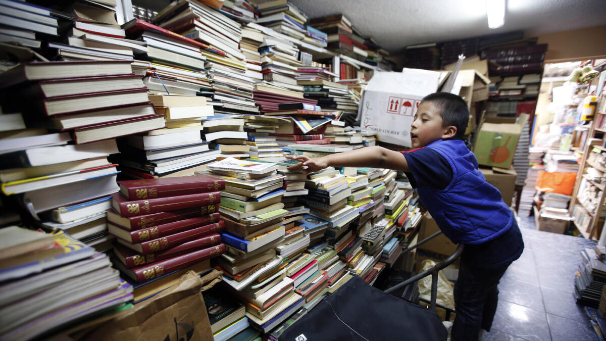 Cristian Orjuela, 5, looks for a book at Jose Alberto Gutierrez's home in Bogota, Colombia.
