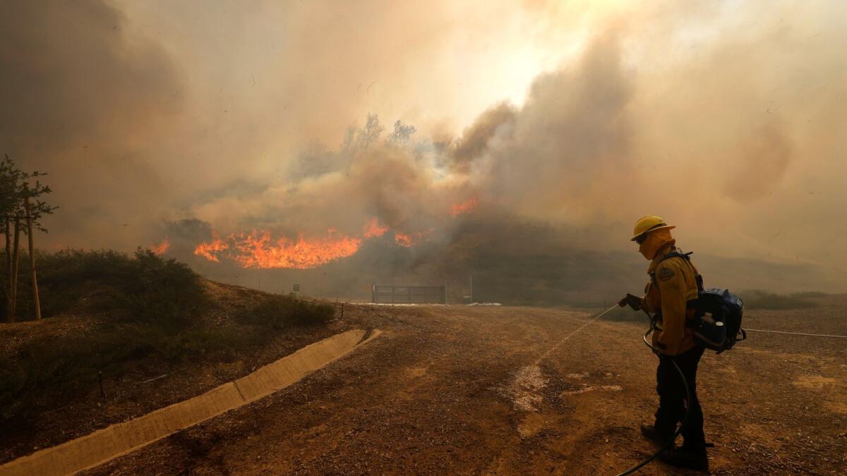 A firefighter carries a hose as the Silverado Fire is approaching, near Irvine, California, U.S. October 26, 2020.