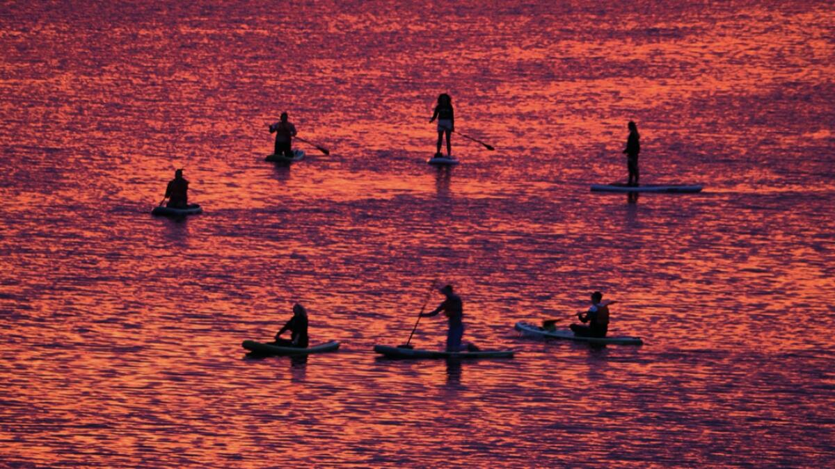 People steer their stand-up paddle boards at sunset on the Velikaya River in Pskov, South-West of St. Petersburg, Russia. Photo: AP