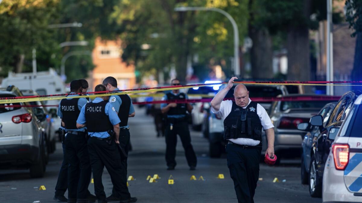Chicago police officers investigate the scene of a deadly shooting where a 7-year-old girl and a man were fatally shot in Chicago. At least a dozen people were killed in Chicago over the Fourth of July weekend, police said. Scores of people were shot and wounded. AP