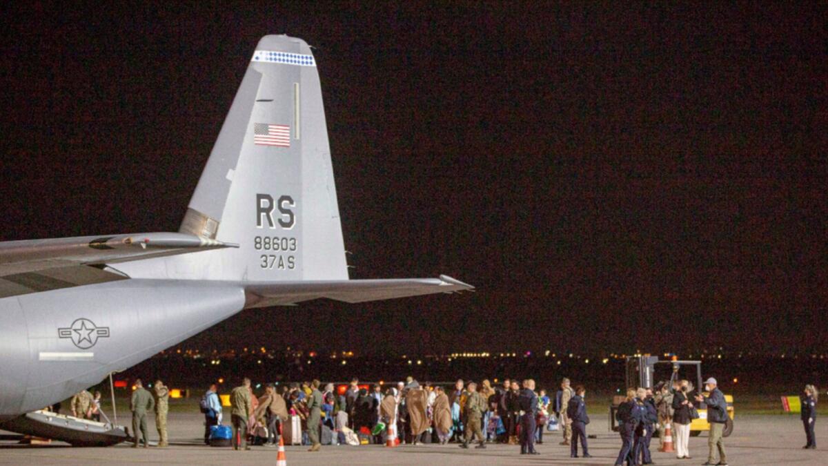 Families evacuated from Kabul walk past a US Air Force plane that they arrived on at Kosovo's Pristina International Airport. — AP