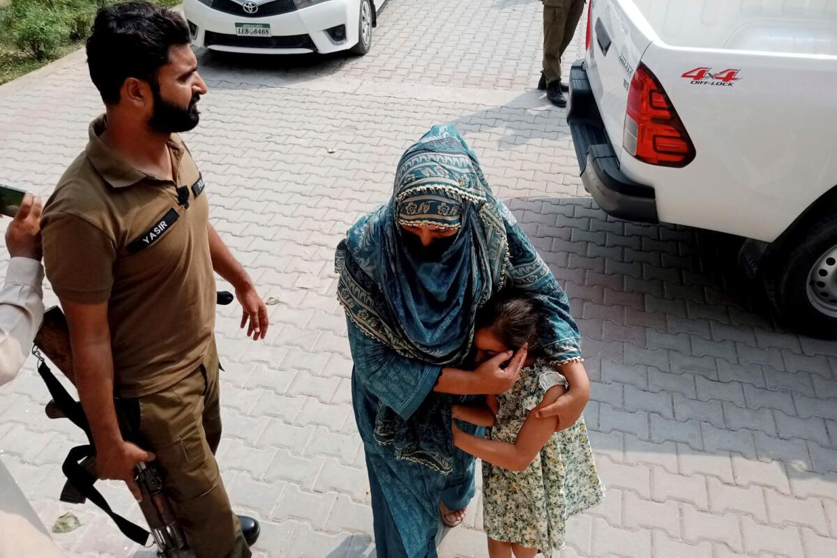 Police officers escort a relative and a child of a couple wanted by British police in connection with last month's death of their 10-year-old daughter on the outskirts of London, to appear them in a court in Jhelum on Tuesday. — AP