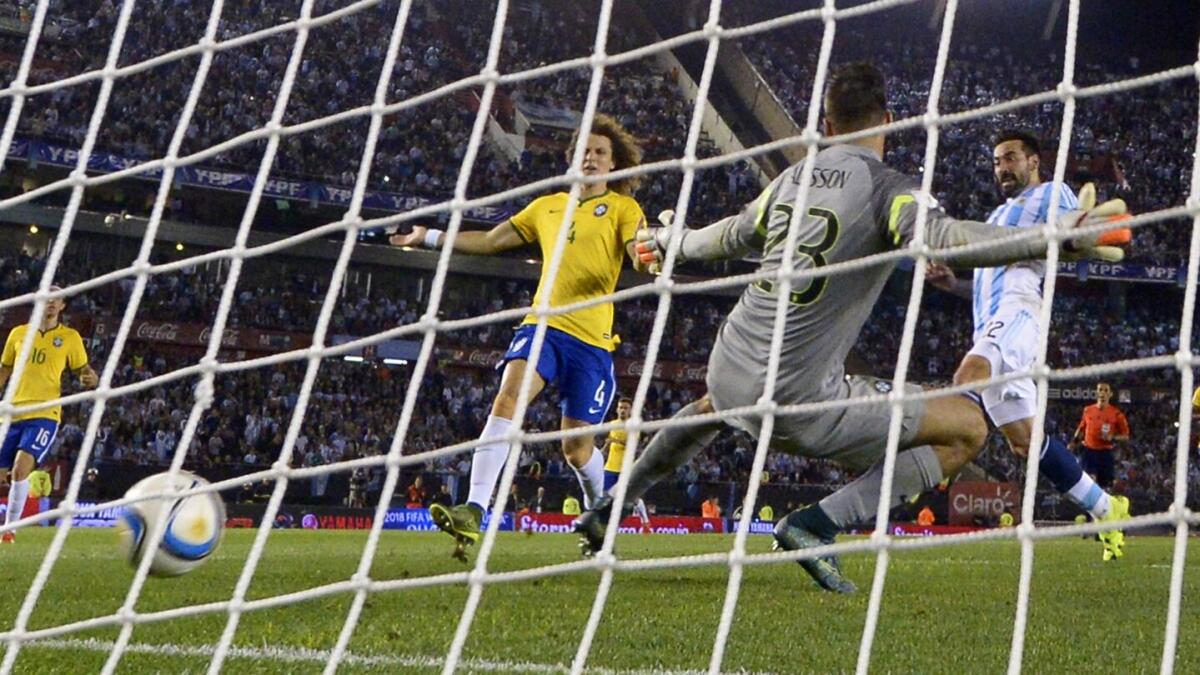 Argentina’s forward Ezequiel Lavezzi (right) scores past Brazil goalkeeper Alisson (23) and David Luiz. 