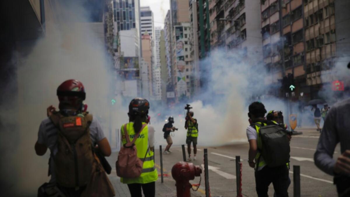 Members of the media take cover as police fire tear gas during a protest against Beijing's national security legislation in Causeway Bay in Hong Kong, Sunday, May 24.