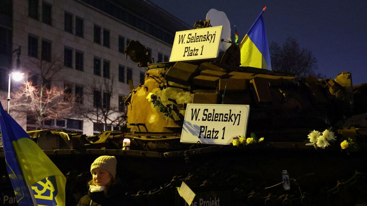 A person holds a Ukrainian flag in front of a tank as people take part in a protest to mark the one-year anniversary of the Russia-Ukraine war in Berlin. — Reuters