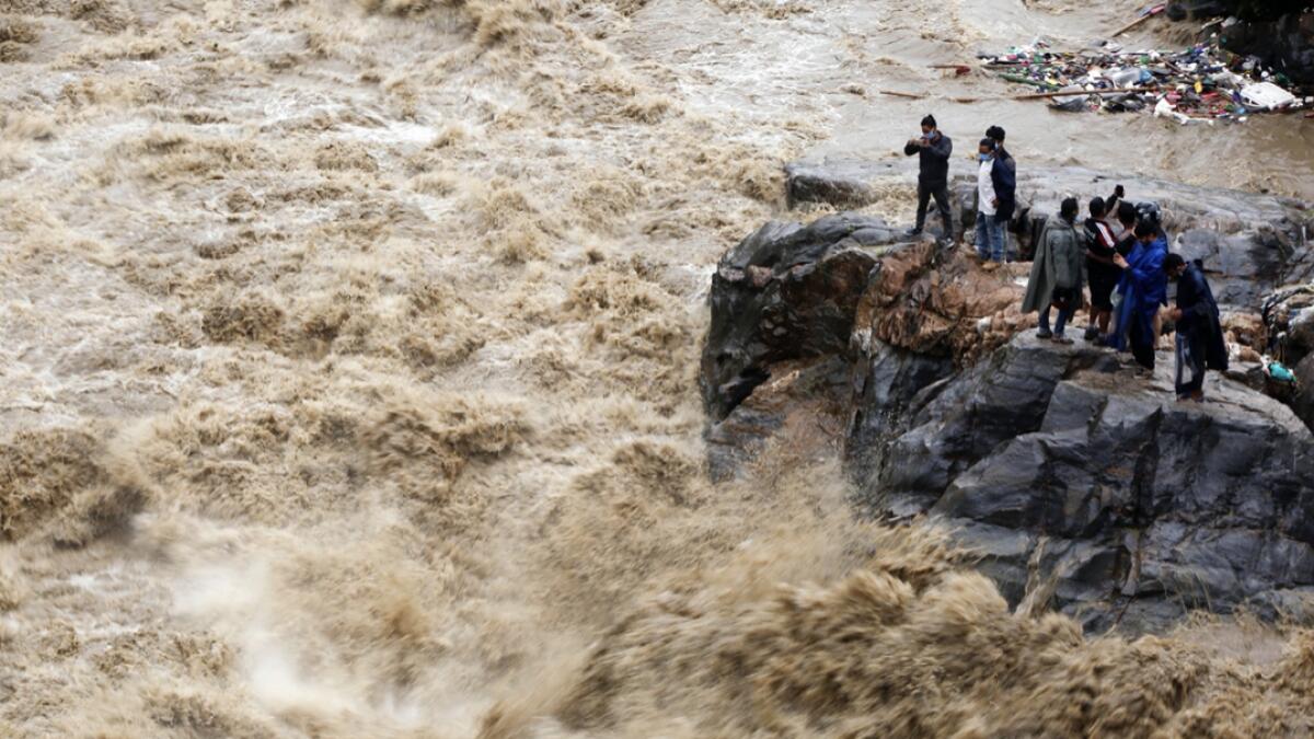 Nepalese people takes photos on the banks of flooded Bagmati river in Kathmandu, Nepal. Landslides and flooding caused by continuous heavy rainfall has blocked the main highway that connects Nepal's capital to most of the Himalayan nation blocking trucks bringing fuel and supplies. Photo: AP