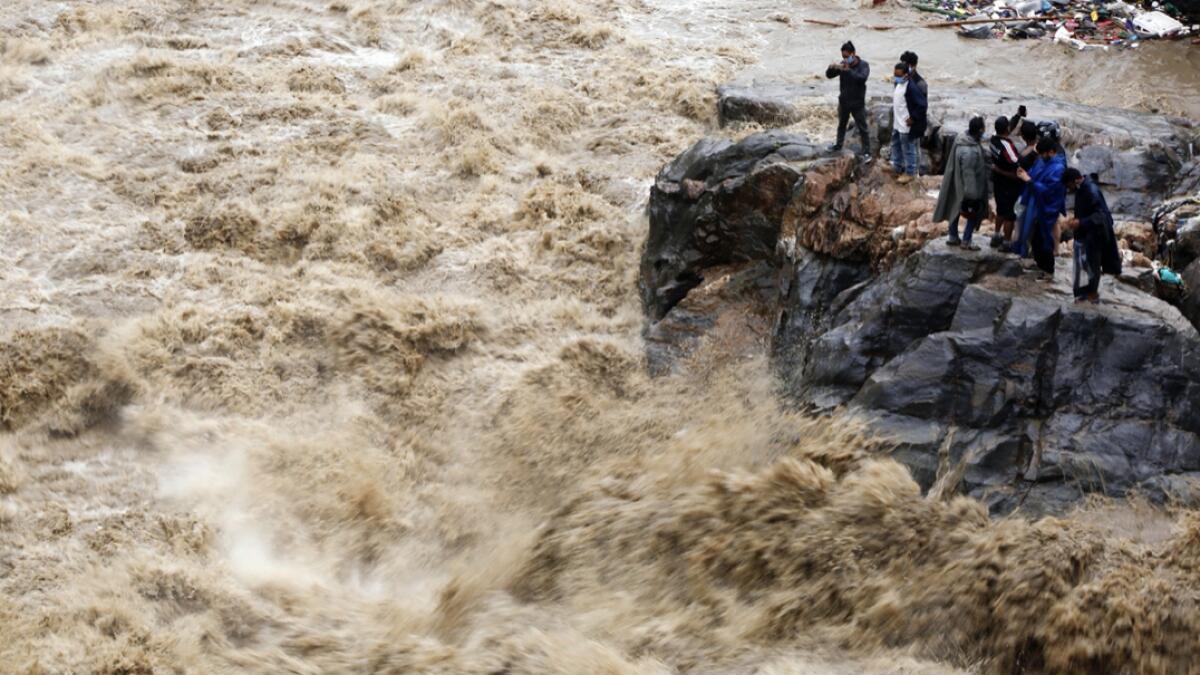 Nepalese people takes photos on the banks of flooded Bagmati river in Kathmandu, Nepal. Landslides and flooding caused by continuous heavy rainfall has blocked the main highway that connects Nepal's capital to most of the Himalayan nation blocking trucks bringing fuel and supplies. Photo: AP