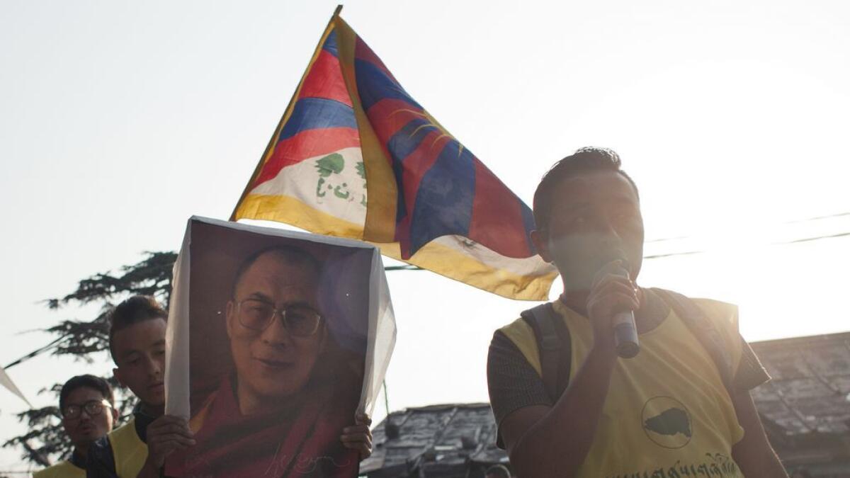 Exile Tibetans carry a portrait of their spiritual leader the Dalai Lama and a Tibetan flag during a candlelit vigil in solidarity with two Tibetans, who exiles claim have immolated themselves demanding freedom for Tibet, in Dharmsala, India, Wednesday, March 2, 2016.