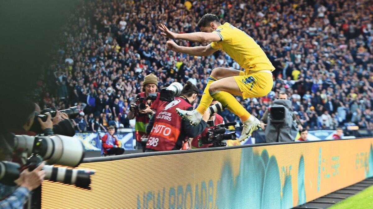 Ukraine's striker Roman Yaremchuk jumps the advertising hoardings as he celebrates scoring the team's second goal against Scotland. — AFP