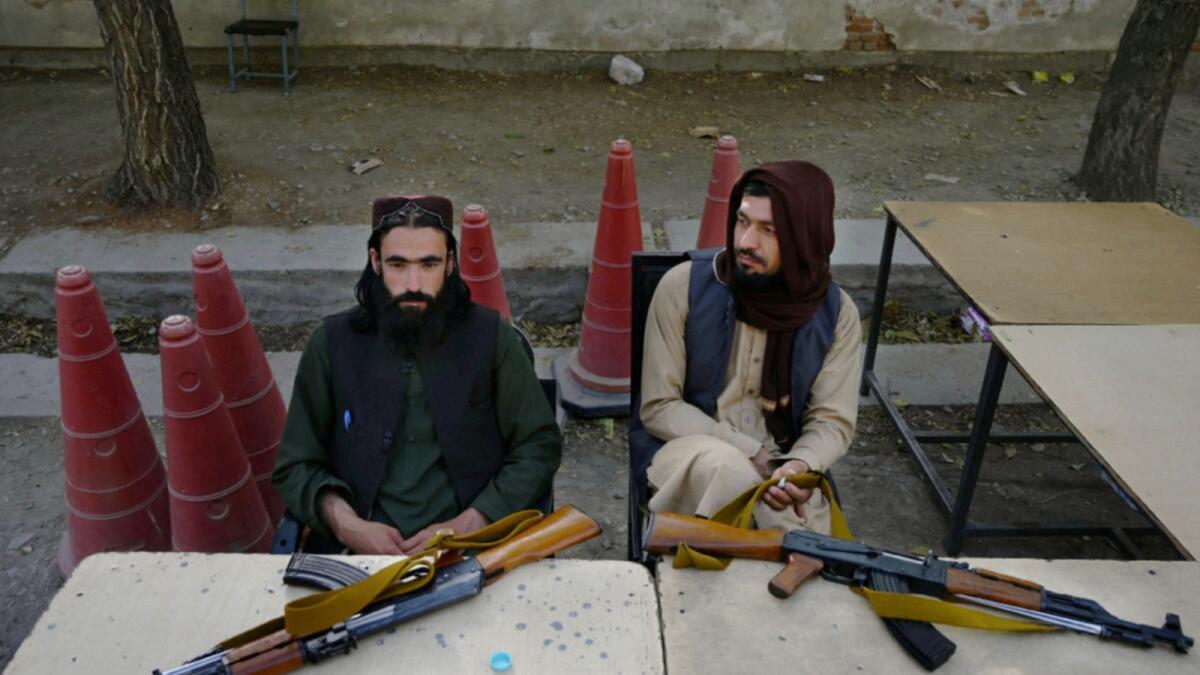 Taliban fighters sit outside the passport office after Taliban announced the reopening for passport applications, in Kabul. — AFP