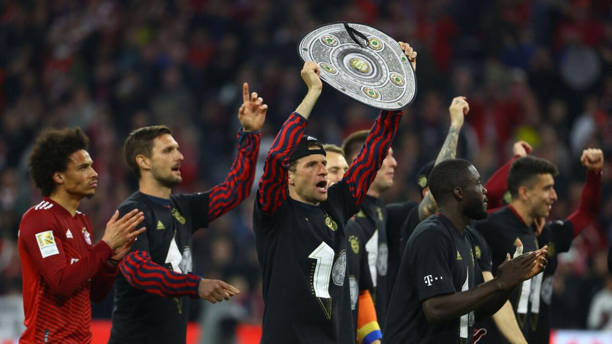 Bayern Munich's Thomas Muller celebrates with a replica trophy and teammates after winning the Bundesliga. (Reuters)
