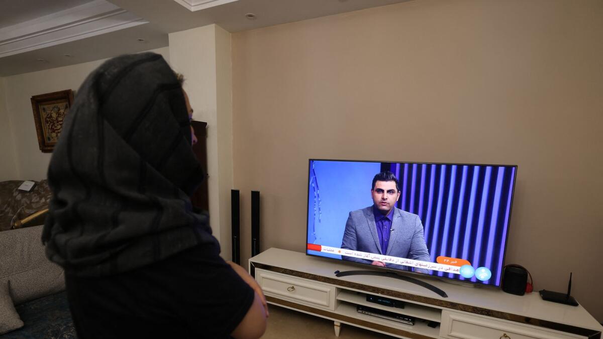 An Iranian woman in Tehran watches an Iranian news TV channel covering news of the attack on Israel. Photo: AFP