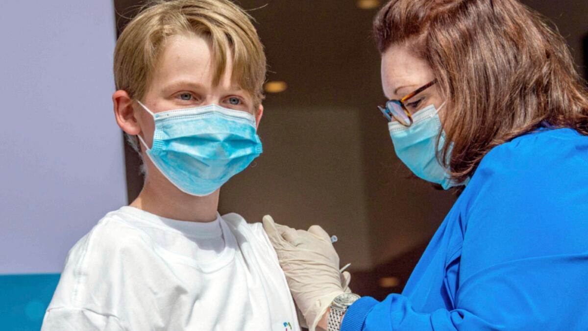 Charles Muro, age 13, is inoculated by Nurse Karen Pagliaro at Hartford  Healthcare's mass vaccination centre at the Connecticut Convention Center in Hartford, Connecticut. — AFP