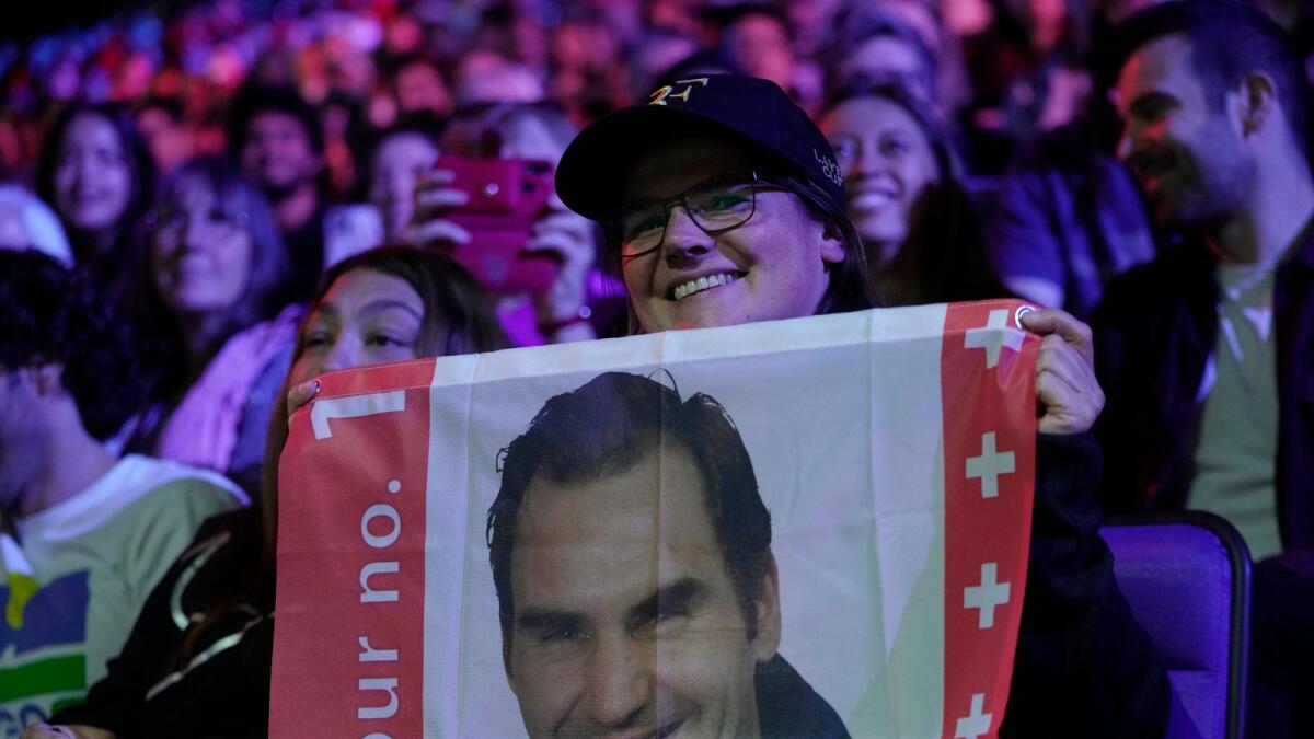 A fan holds a flag with a picture of Roger Federer. — AP