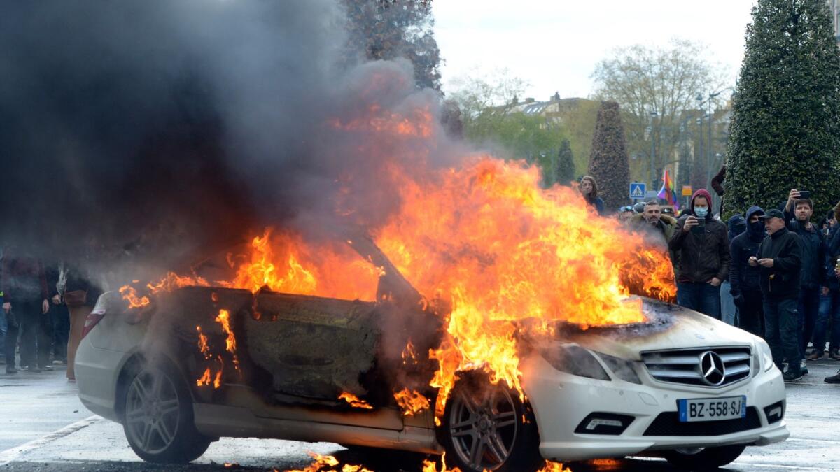 Protesters watch a burning car during a demonstration on Thursday in Rennes, western France. — AP