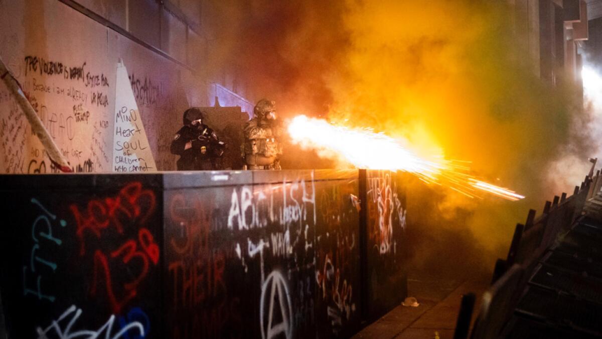 Federal agents use crowd control munitions to disperse Black Lives Matter protesters at the Mark O. Hatfield United States Courthouse, in Portland. Officers used teargas and projectiles to move the crowd after some protesters tore down a fence fronting the courthouse. Photo: AP