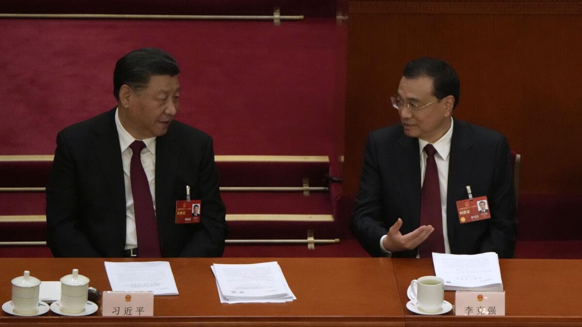Chinese President Xi Jinping, left, and Premier Li Keqiang talk during the opening session of China's National People's Congress (NPC) at the Great Hall of the People in Beijing on Sunday. - AP