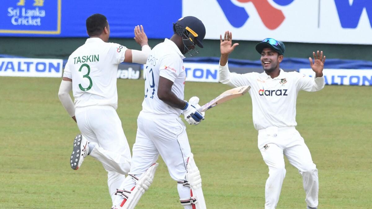 Bangladesh's Taskin Ahmed (left) celebrates with teammate Mehidy Hasan after dismissing Sri Lanka's Angelo Mathews (centre) during the second day of the second Test. (AFP)