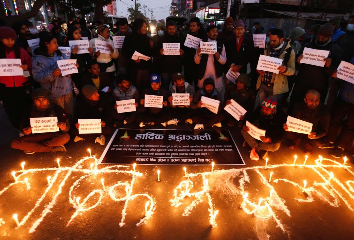 People hold placards as they take part in a condolence and protest meeting following the plane cras. Photo: Reuters