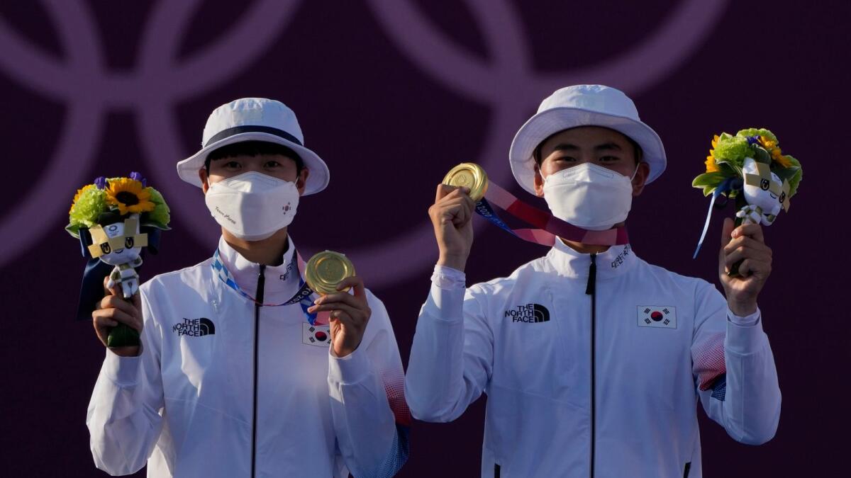 Gold medal winners South Korea's An San (left) and South Korea's Kim Je Deok celebrate on the podium of a mixed team competition at the 2020 Summer Olympics. — AP