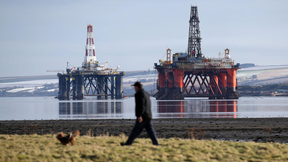 A man walks past oil platforms near Invergordon in the Highlands of Scotland. A combination of factors will impact oil prices in the new year. - AP file