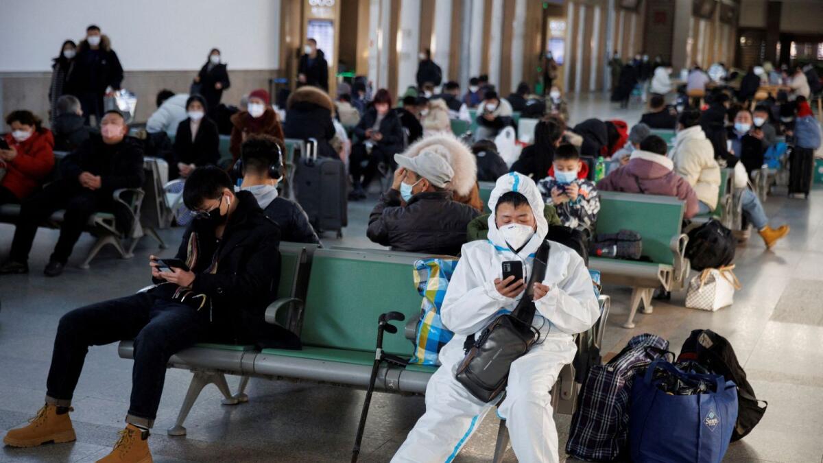 A person wearing a protective suit sits at Beijing Railway Station as passengers wait to board a train to travel for Spring Festival ahead of Chinese Lunar New Year festivities. — Reuters file