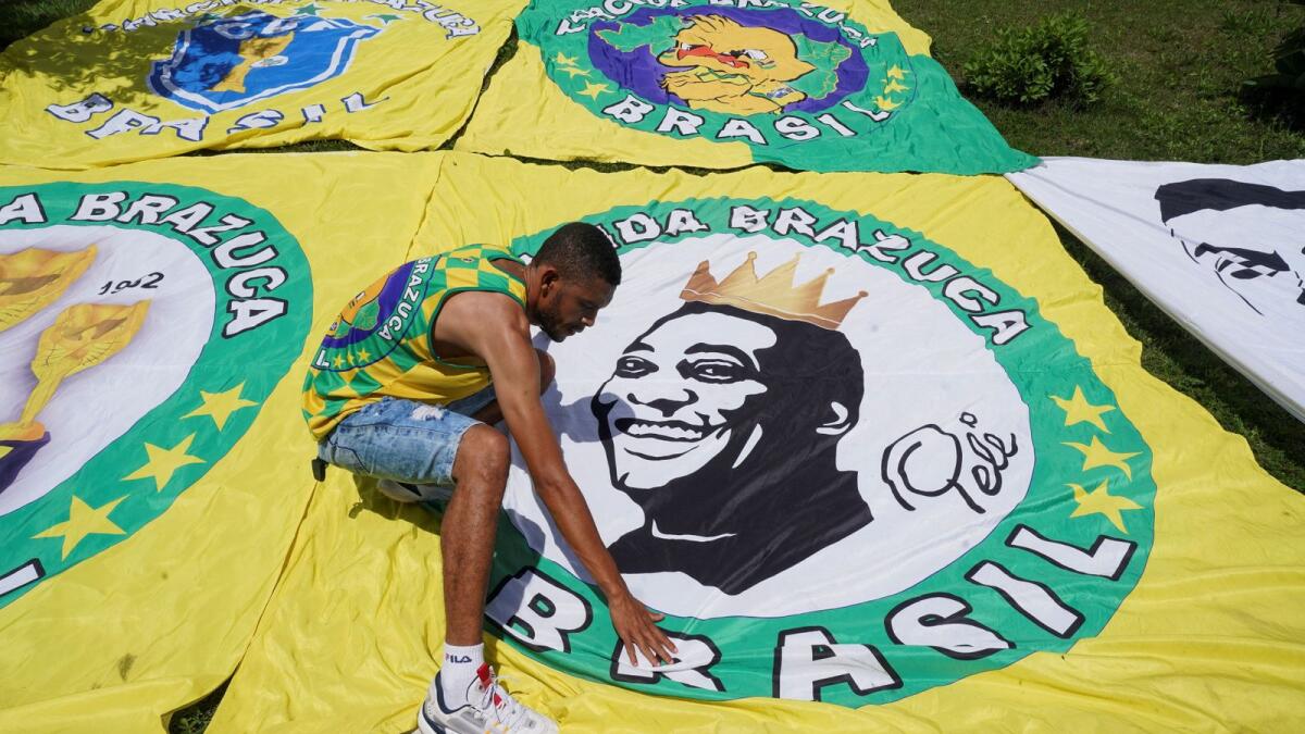 A fan places a flag with the image of Brazilian legend Pele in Tres Coracoes, the city where Pele was born. — Reuters