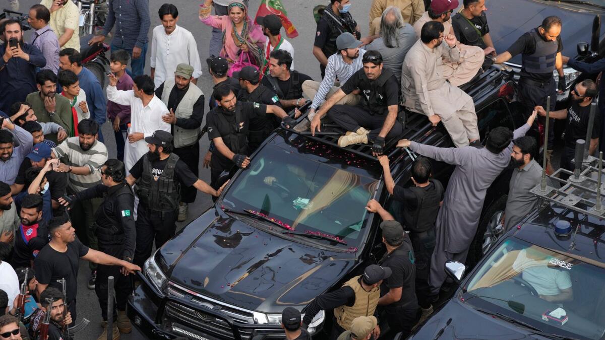 Security personnel and supporters move with a vehicle (centre) carrying former prime minister Imran Khan during an election campaign rally in Lahore on Monday. — AP