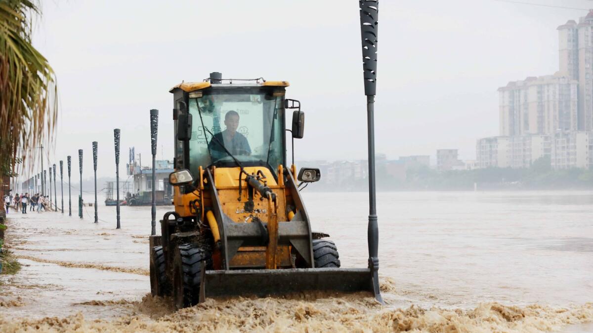 A worker uses a bulldozer to clear a flooded street caused by heavy rains in Rongan in China's southern Guangxi region. Photo: AFP