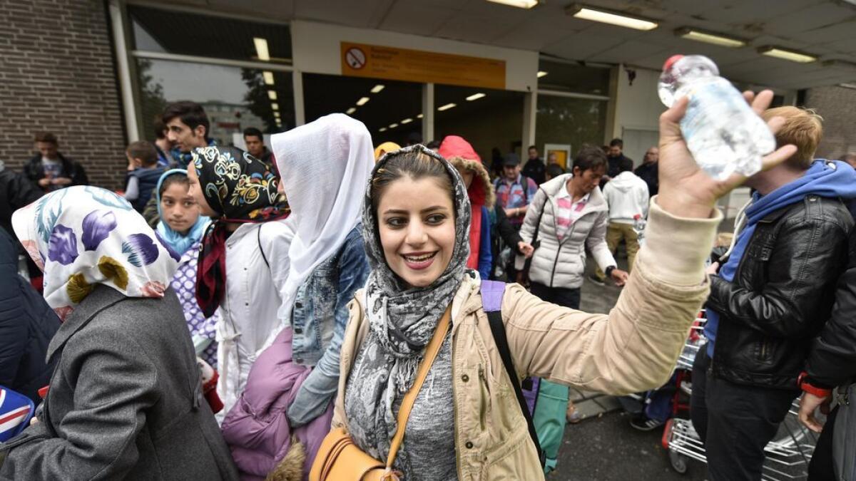 Refugees wave to applauding people in Dortmund, Germany.