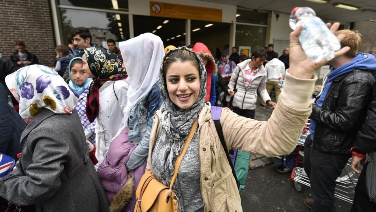 Refugees wave to applauding people in Dortmund, Germany.