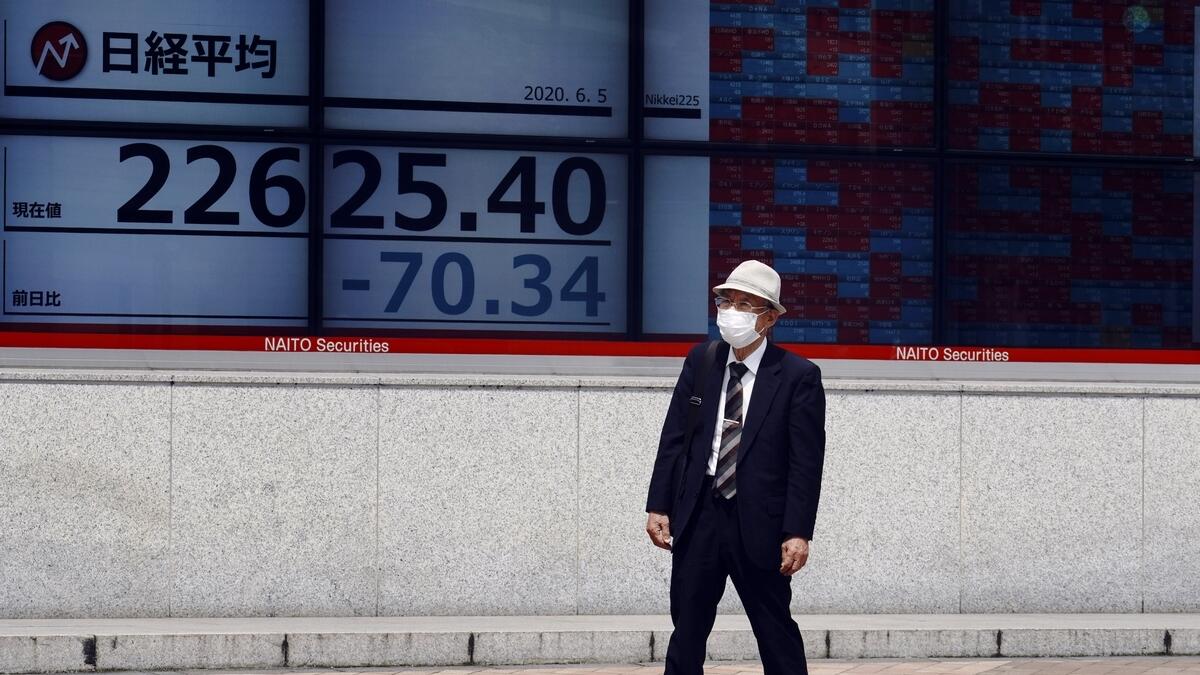 A man stands in front of an electronic stock board showing Japan's Nikkei 225 index at a securities firm in Tokyo on Friday. - AP