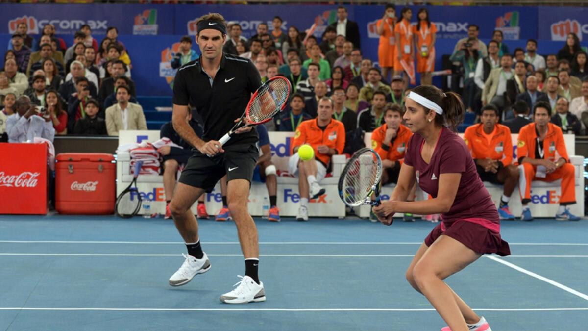 Roger Federer looks on as his Indian Aces' teammate Sania Mirza (right) returns the ball during the International Premier Tennis League (IPTL) match in this picture dated December 7, 2014. — AFP file