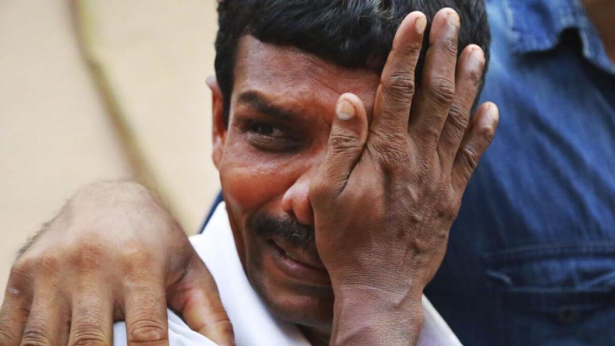An unidentified man weeps as bodies of victims lie outside a morgue at the Kollam district hospital after a massive fire broke out during a fireworks display at the Puttingal temple complex in Paravoor village, Kollam district, southern Kerala state, Indi