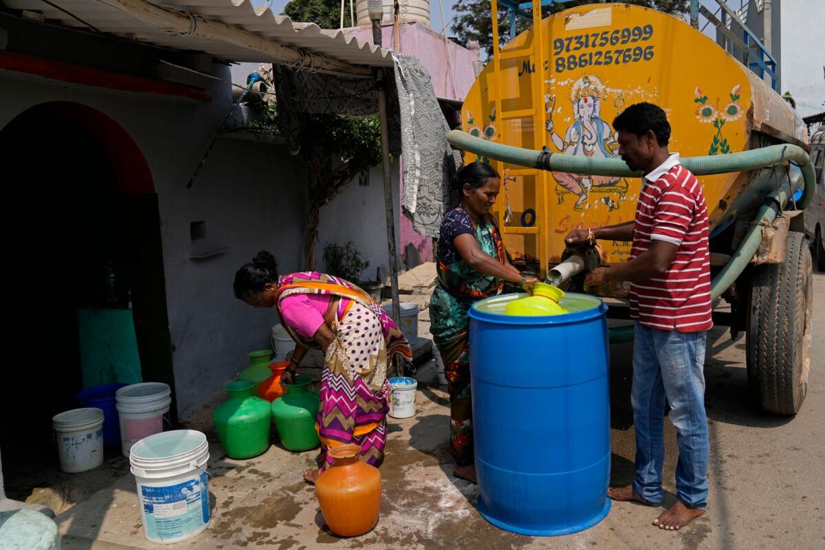 Residents of Ambedkar Nagar, a low-income settlement in the shadows of global software companies in Whitefield neighbourhood, collect potable water from a private tanker in Bengaluru, India, on March 11, 2024.  — AP