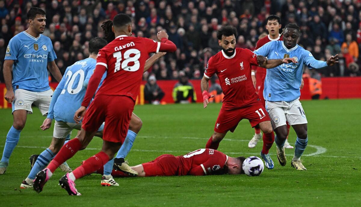 Play continues as Liverpool's Argentinian midfielder Alexis Mac Allister lays on the pitch after a challenge from Manchester City's Belgian midfielder Jeremy Doku during the English Premier League. - AFP