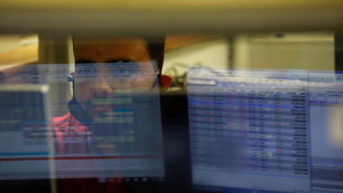 A computer screen is reflected in the glass window of a booth where a broker is monitoring the market in the halls of the Pakistan Stock Exchange. Photo: Reuters