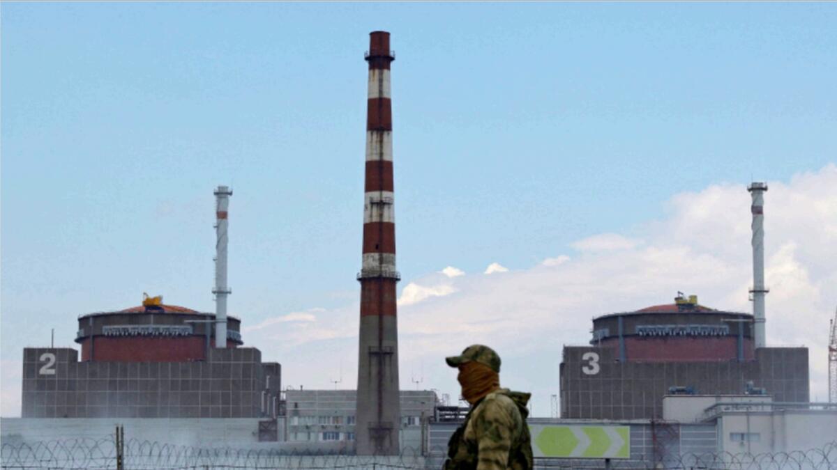A serviceman with a Russian flag on his uniform stands guard near the Zaporizhzhia Nuclear Power Plant. — Reuters file