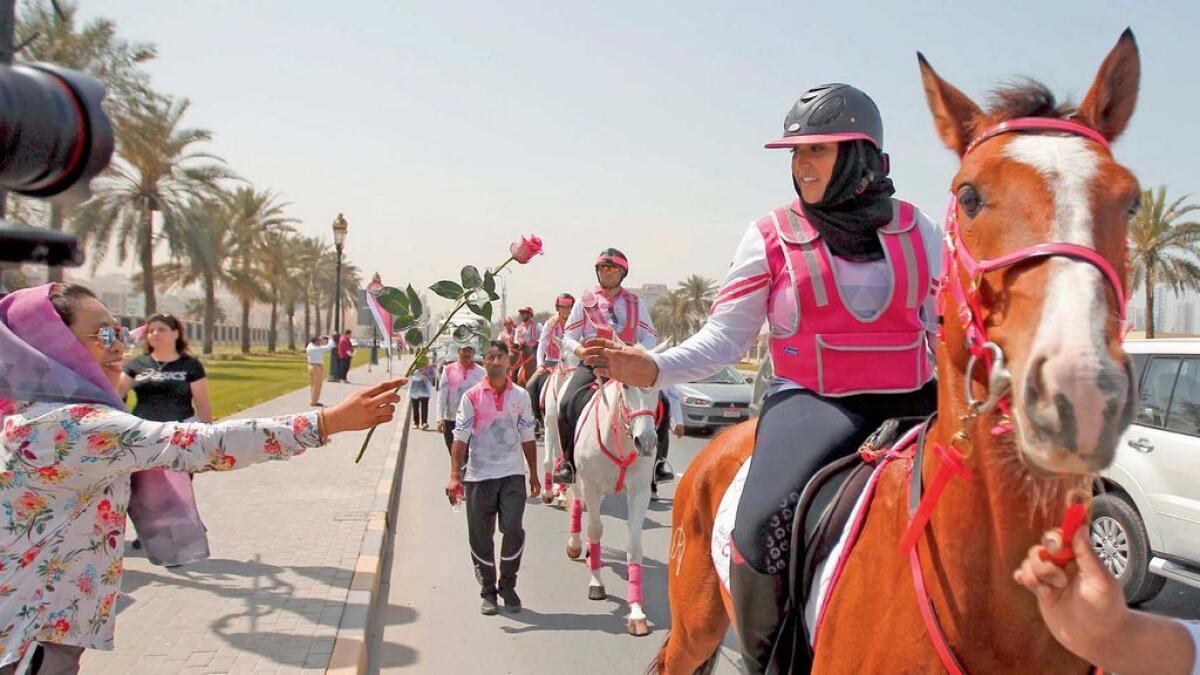 A resident hands over a flower to a rider as the caravan progresses from Ajman to Sharjah.