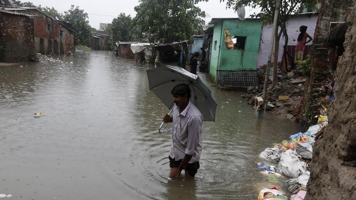 An Indian man wades through flood waters at an area near River Sabarmati in Ahmadabad, India