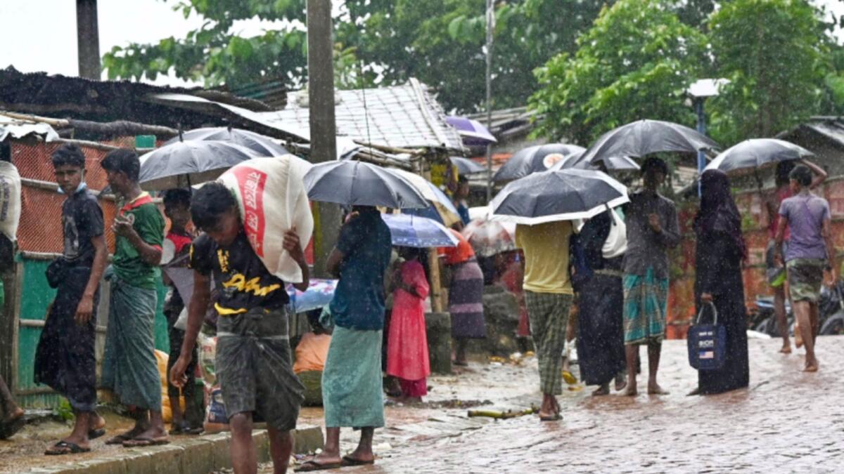 Rohingya refugees wait at a food distribution place during monsoon rains in Kutupalong refugee camp in Ukhia. — AFP
