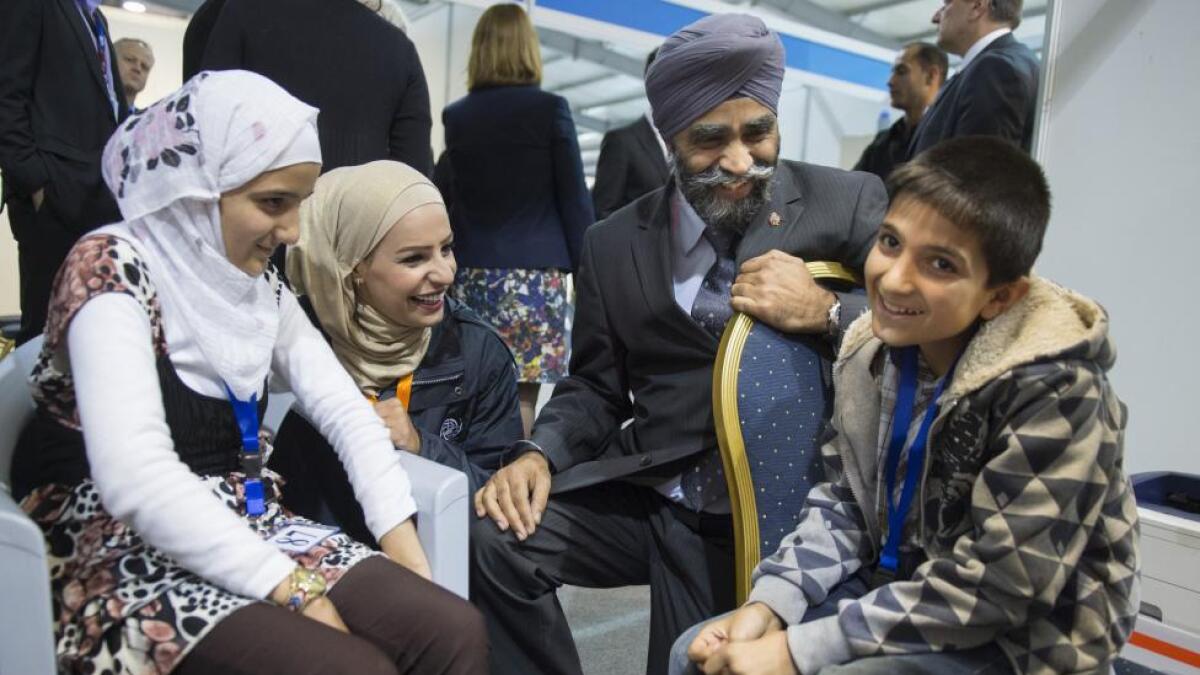 Canadian Minister of National Defence Harjit Sajjan (C) chats with members of a Syrian refugee family being interviewed by authorities in hope of being approved for passage to Canada at a refugee processing center in Amman, Jordan.