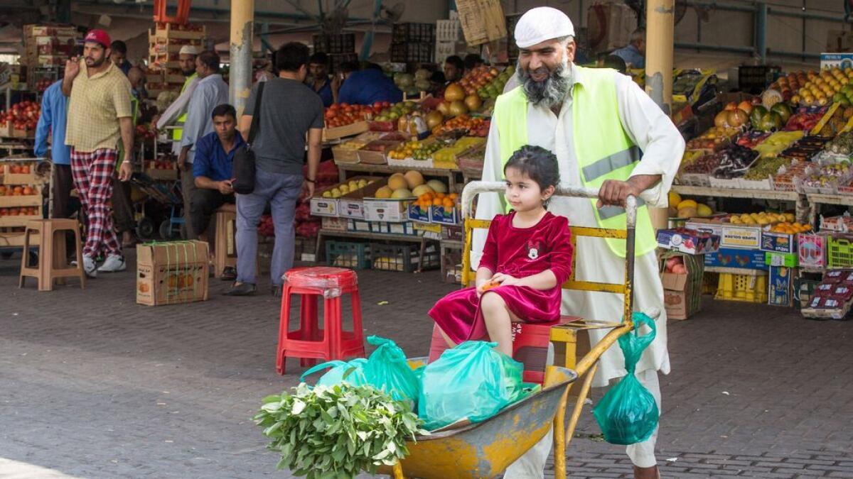 A market worker pushes a customer's purchases and their daughter at the fruit and vegetable market located in Ras Al Khor, Dubai.-Photo by Leslie Pableo/Khaleej Times